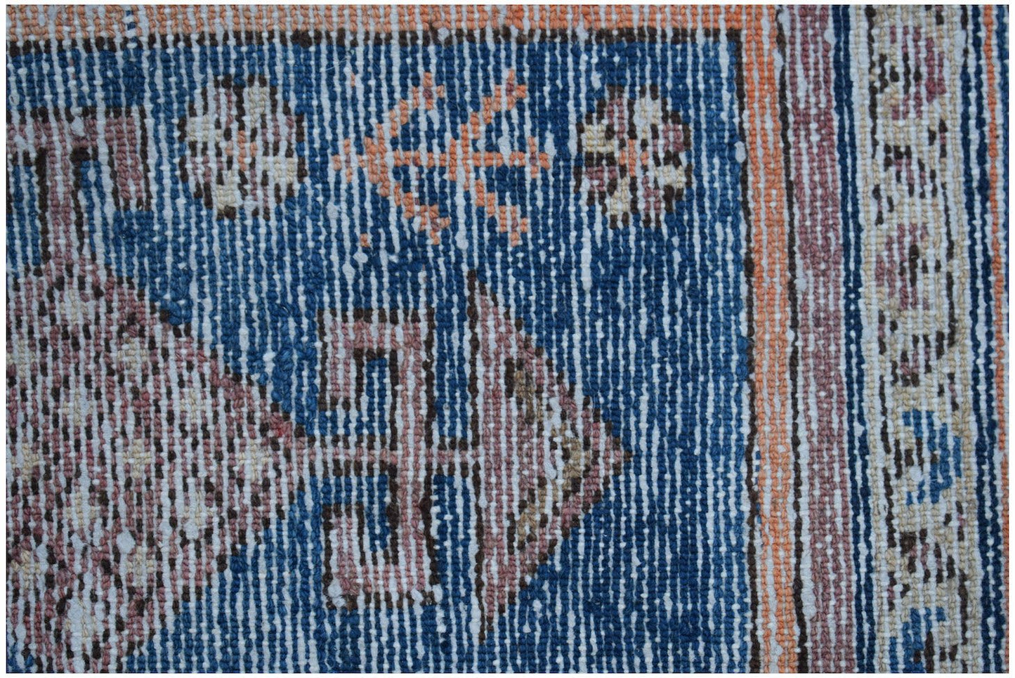 Close-up of a vintage Persian rug with blue, orange, and cream geometric patterns.