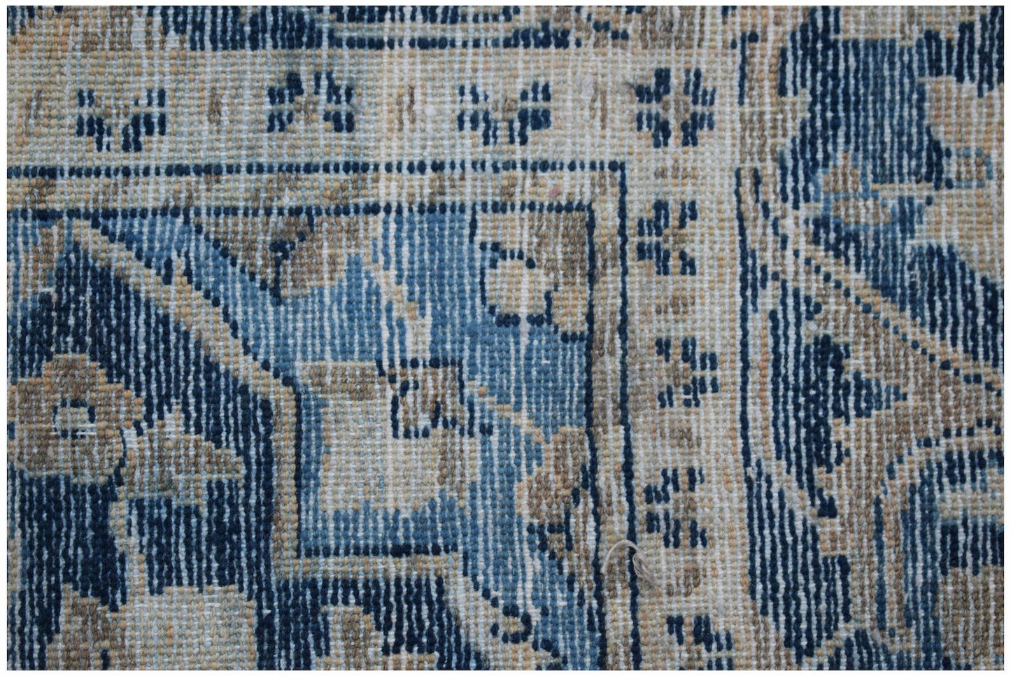 A close-up of a vintage Persian rug featuring intricate blue and beige floral patterns.