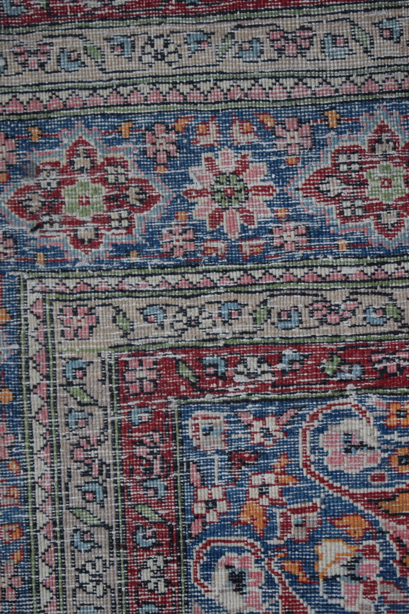 A vintage Persian Mashad rug featuring intricate floral patterns in blue, red, and orange tones.