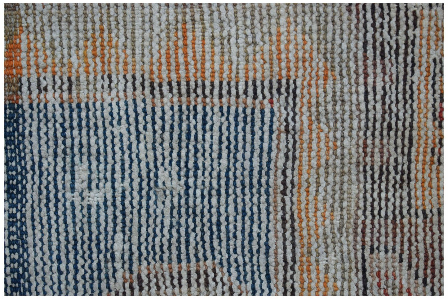 A close-up of a vintage handwoven Persian rug featuring a textured pattern of blue and orange lines.