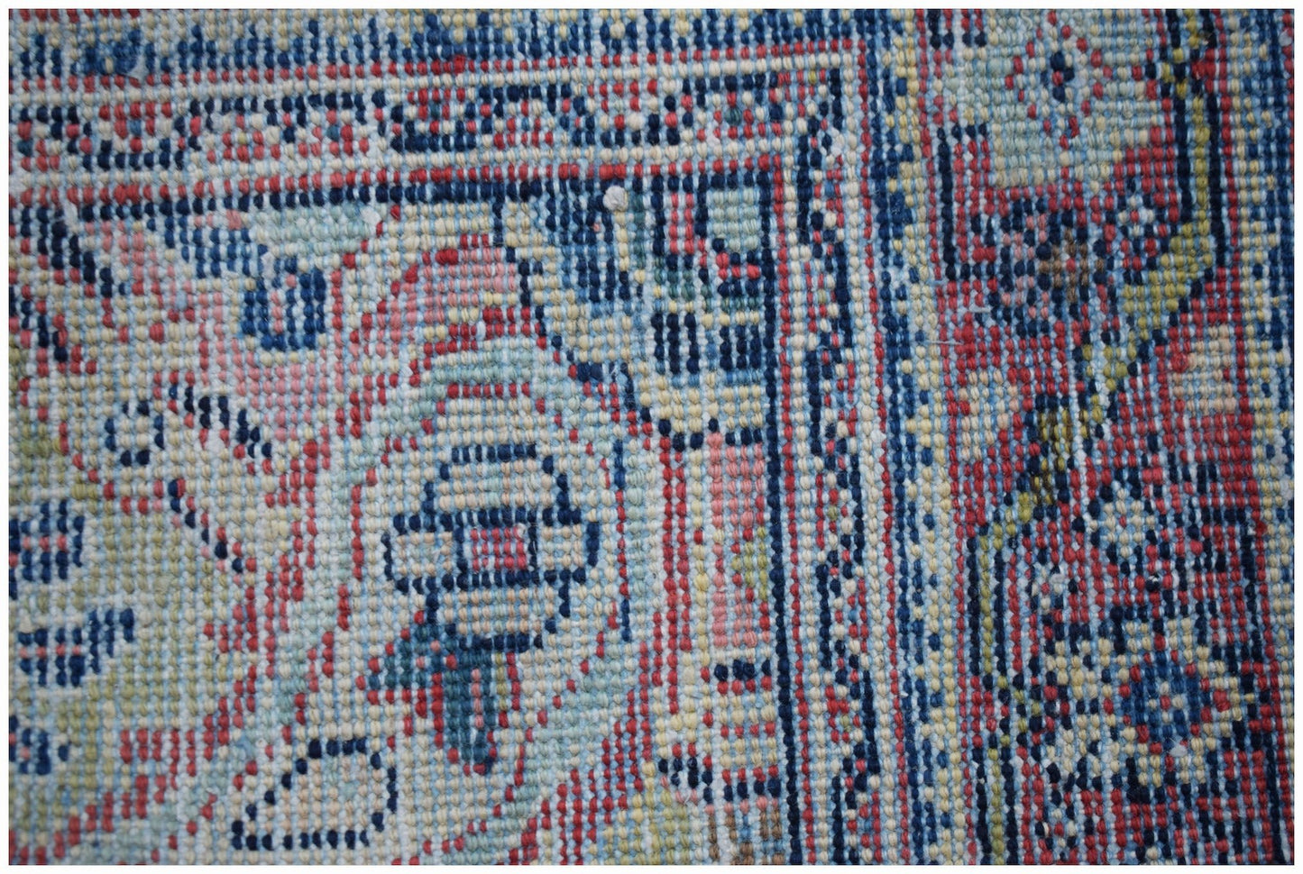 A close-up of a handwoven vintage Persian rug featuring intricate blue and red geometric patterns.