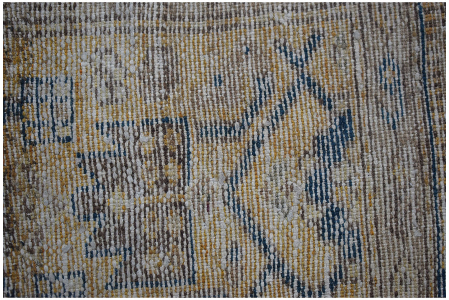 A close-up view of a handwoven vintage Persian rug featuring a faded geometric pattern in wool.