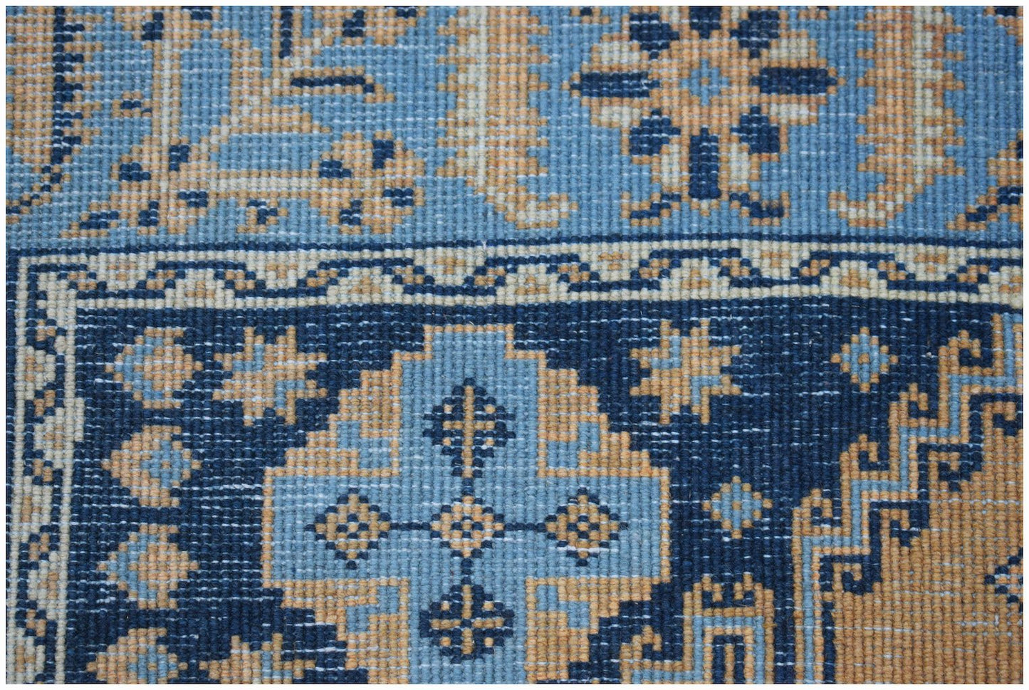 A vintage handwoven Persian rug featuring geometric floral patterns in shades of blue and tan.