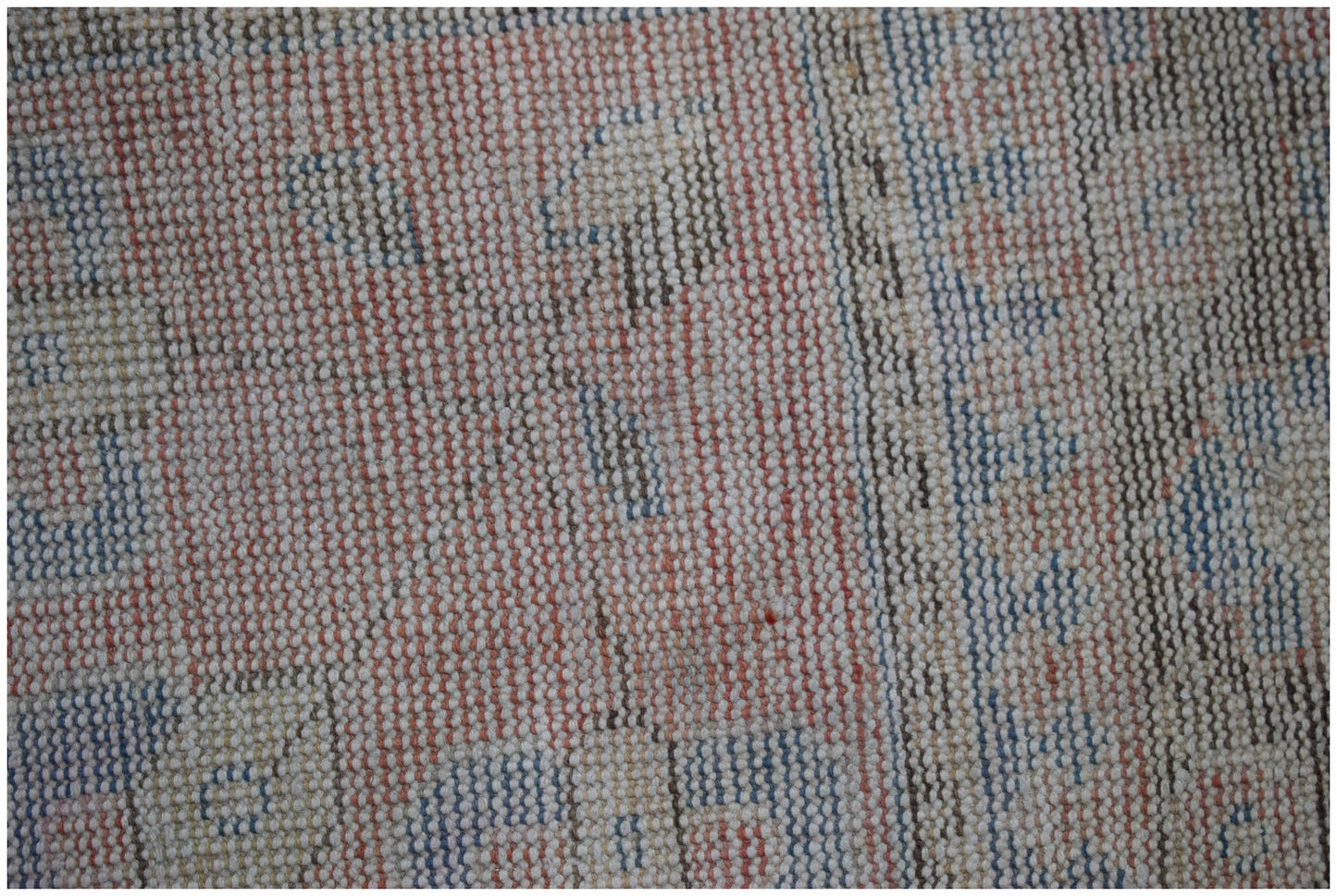 A close-up view of a handwoven vintage Persian rug featuring a faded geometric pattern in wool.