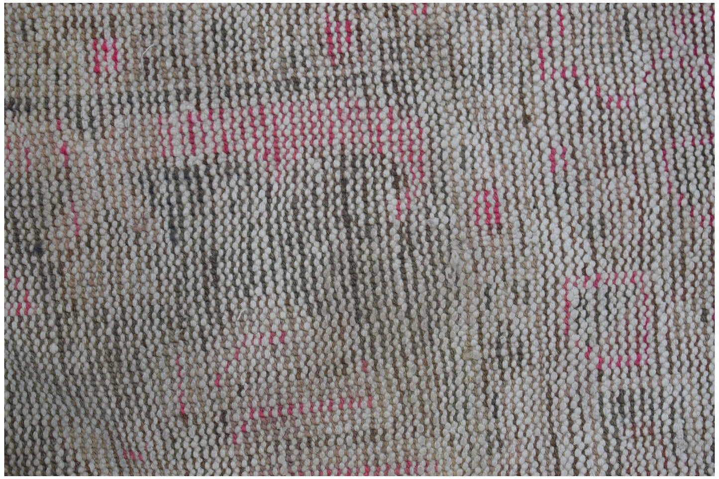 A close-up of a vintage Persian rug featuring a distressed, handwoven wool texture in neutral tones.