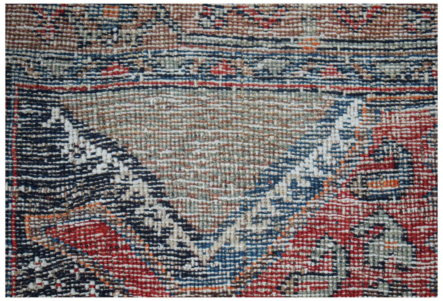 A close-up of a handwoven vintage Persian rug featuring a geometric pattern in red, blue, and tan.