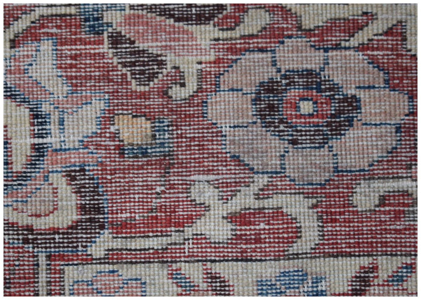 A close-up of a vintage Persian rug featuring intricate floral patterns in red, blue, and cream.