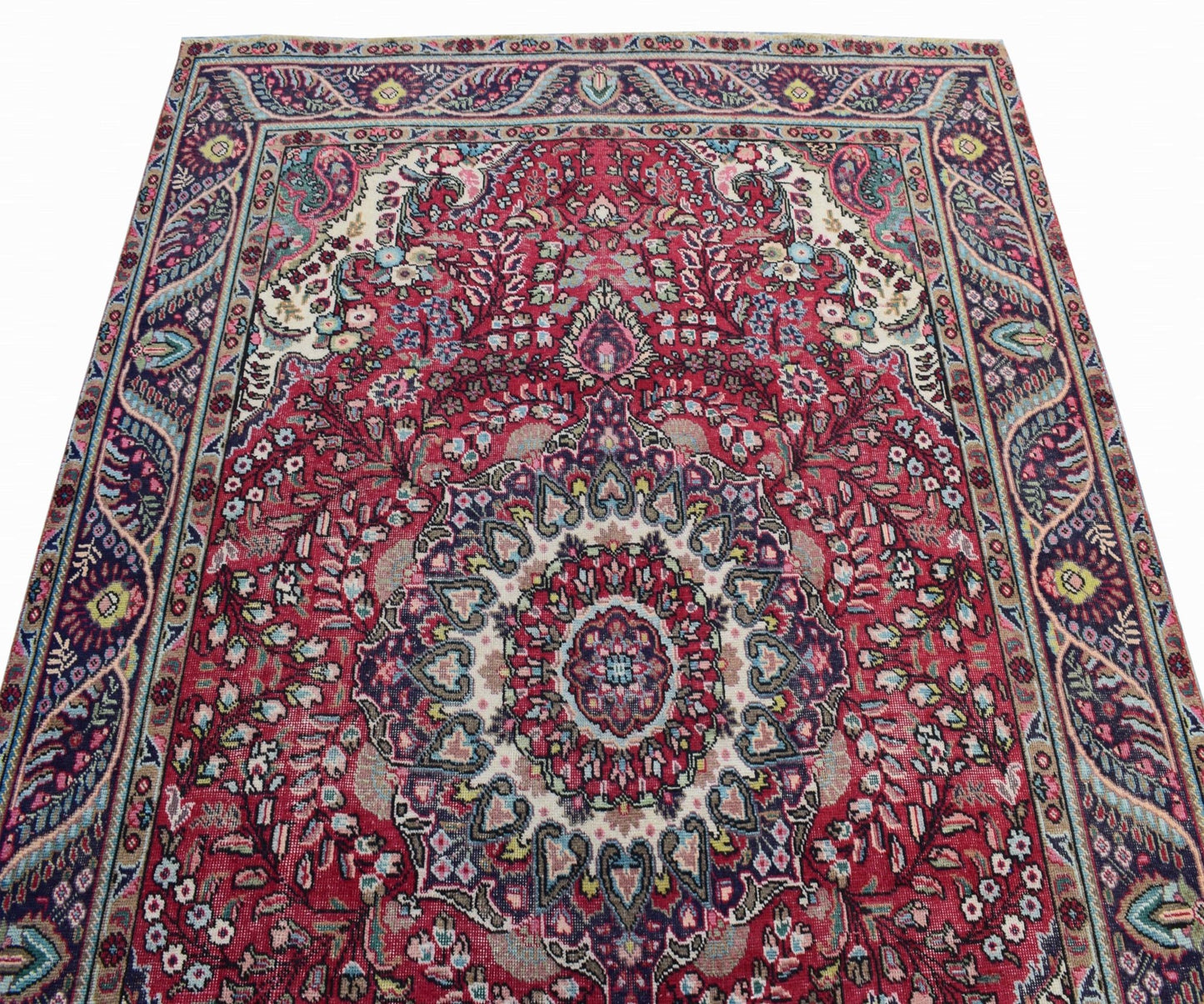 A vintage Persian Tabriz rug featuring an intricate floral medallion design in red and blue tones.