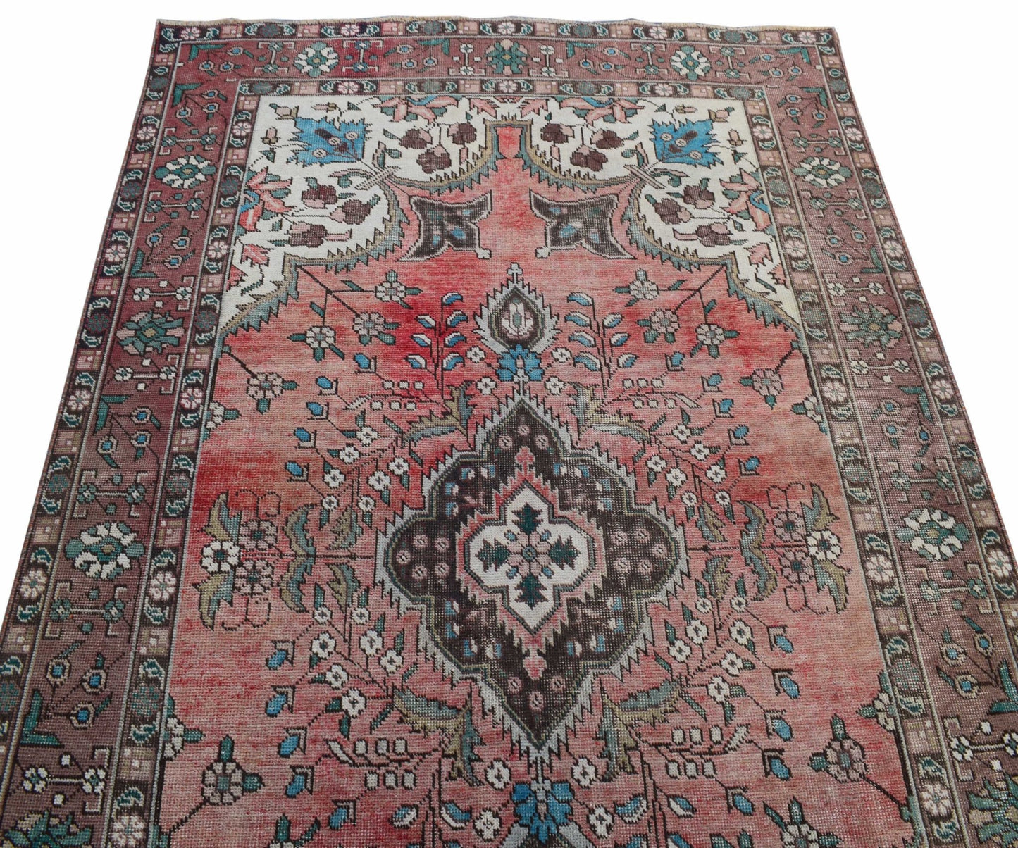 A vintage Persian Tabriz rug featuring a central medallion and intricate floral patterns in pink.
