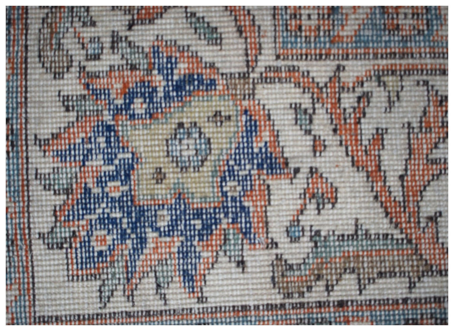 A close-up of a vintage Persian Tabriz rug featuring intricate floral patterns in blue and orange.