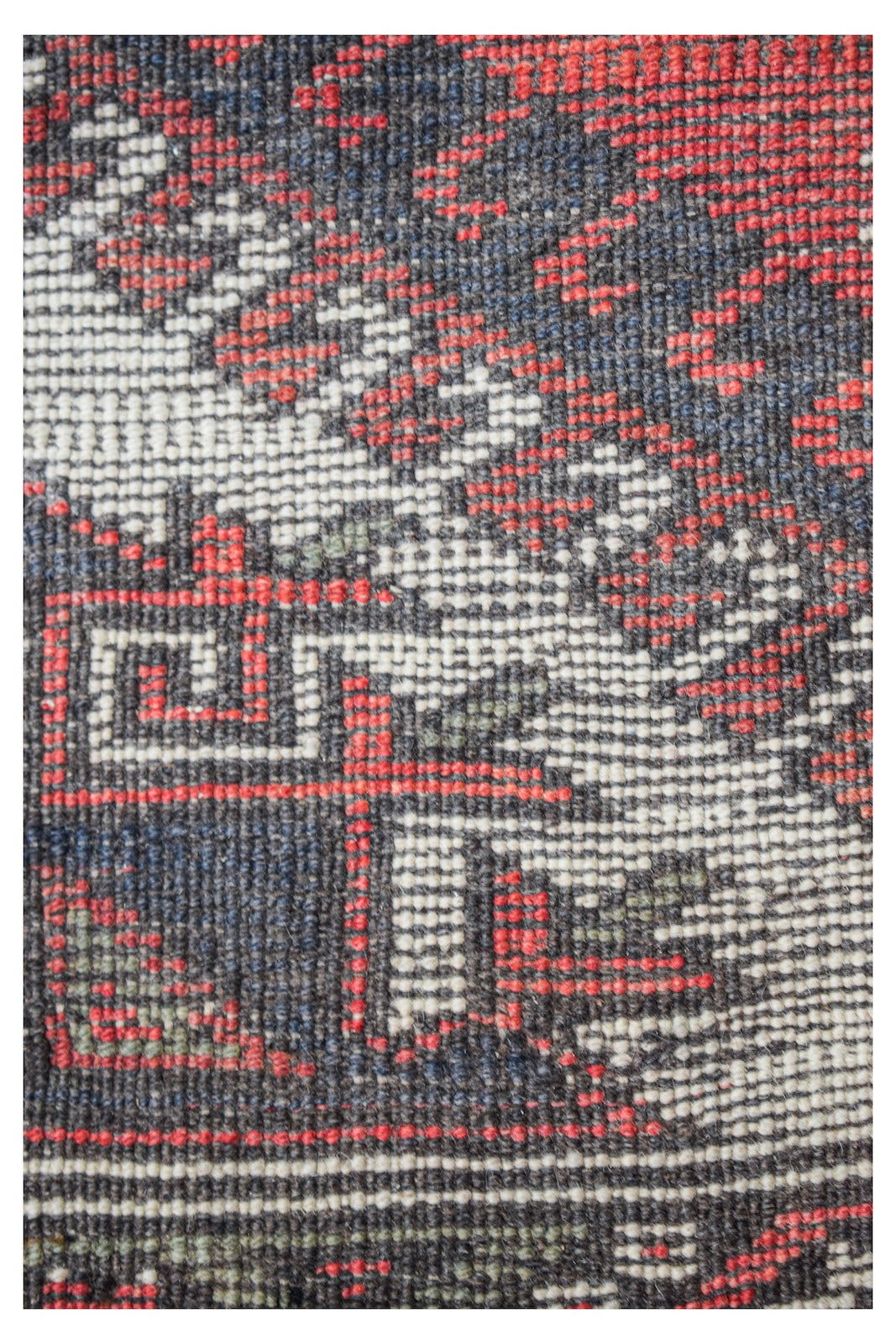 Close-up of a handwoven vintage Persian runner featuring geometric patterns in red, blue, and white.