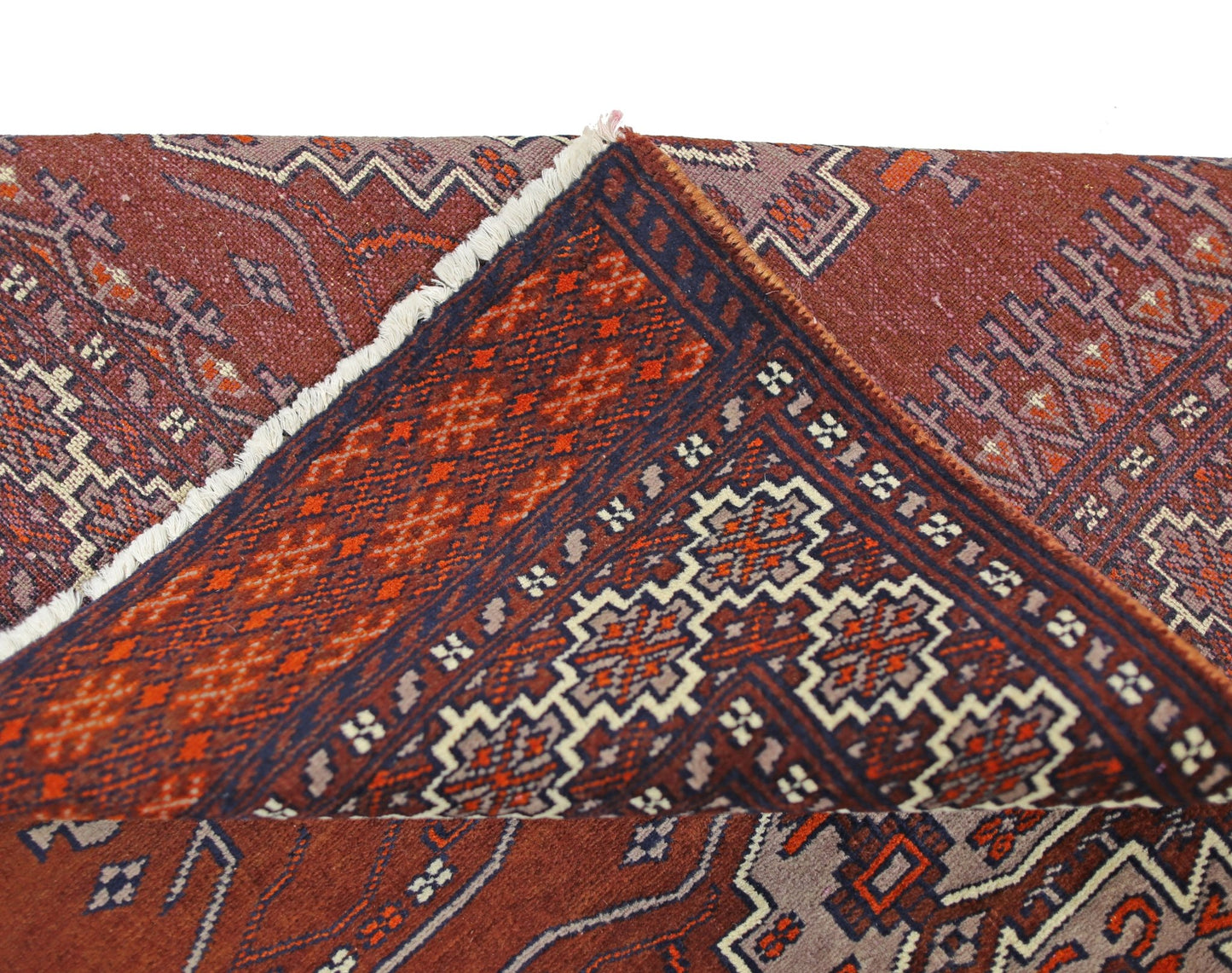 A vintage Pakistani Princess Bokhara rug with a folded corner showing its wool pile and pattern.
