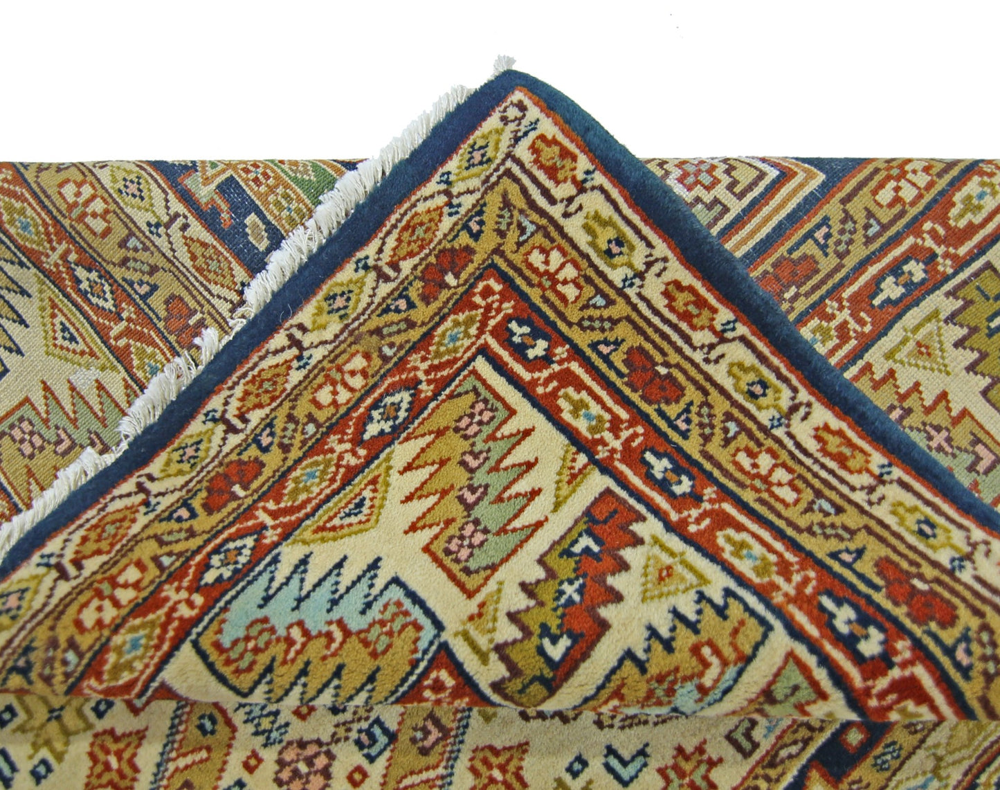 A vintage Pakistani Princess Bokhara rug with a folded corner showing intricate geometric patterns.