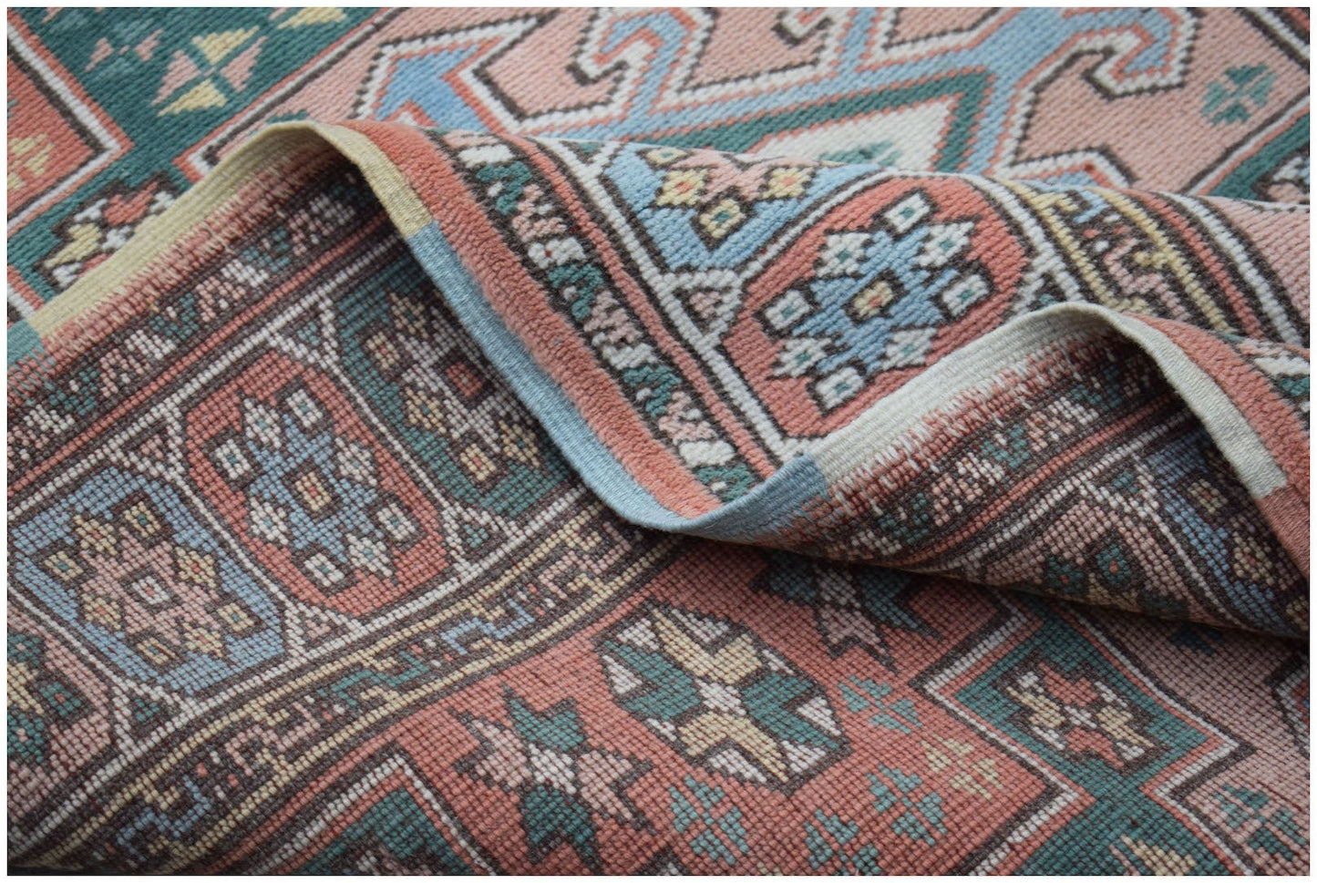 A vintage Turkish Kars runner featuring a geometric pattern in muted pink, blue, and green tones.