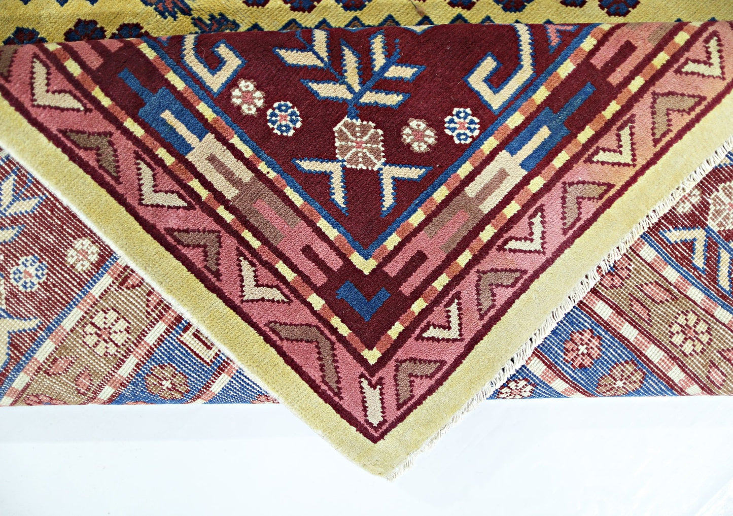 A vintage handmade Turkish rug featuring a geometric floral pattern in red, blue, and yellow tones.