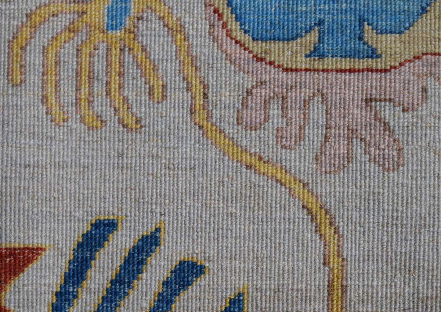 A close-up of an Afghan Chobi runner featuring intricate floral patterns in blue, yellow, and pink.