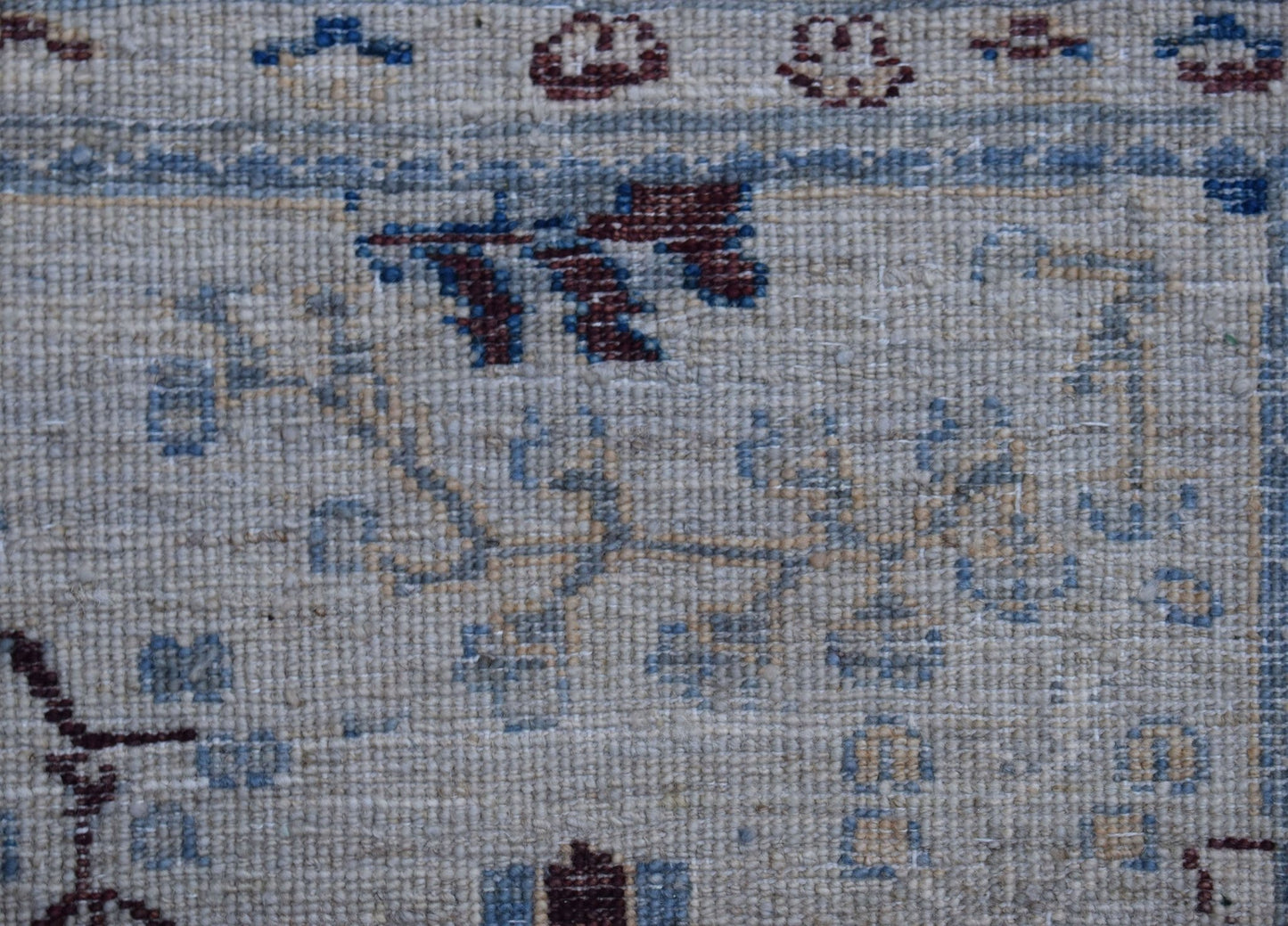 A close-up of a handwoven Afghan Chobi rug featuring traditional floral patterns in wool.