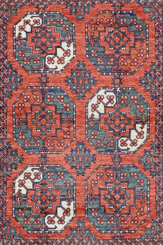 Handwoven Afghan Chobi rug featuring a geometric pattern in shades of red, blue, and cream.