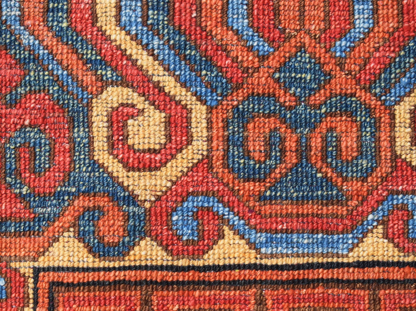 A close-up of an Afghan Chobi rug featuring intricate, hand-woven spiral patterns in wool.