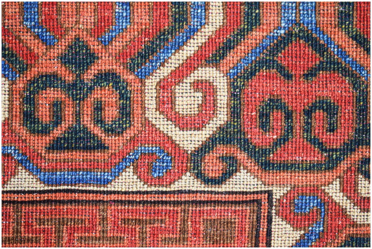 A close-up of an Afghan Chobi rug featuring intricate red, blue, and cream geometric patterns.