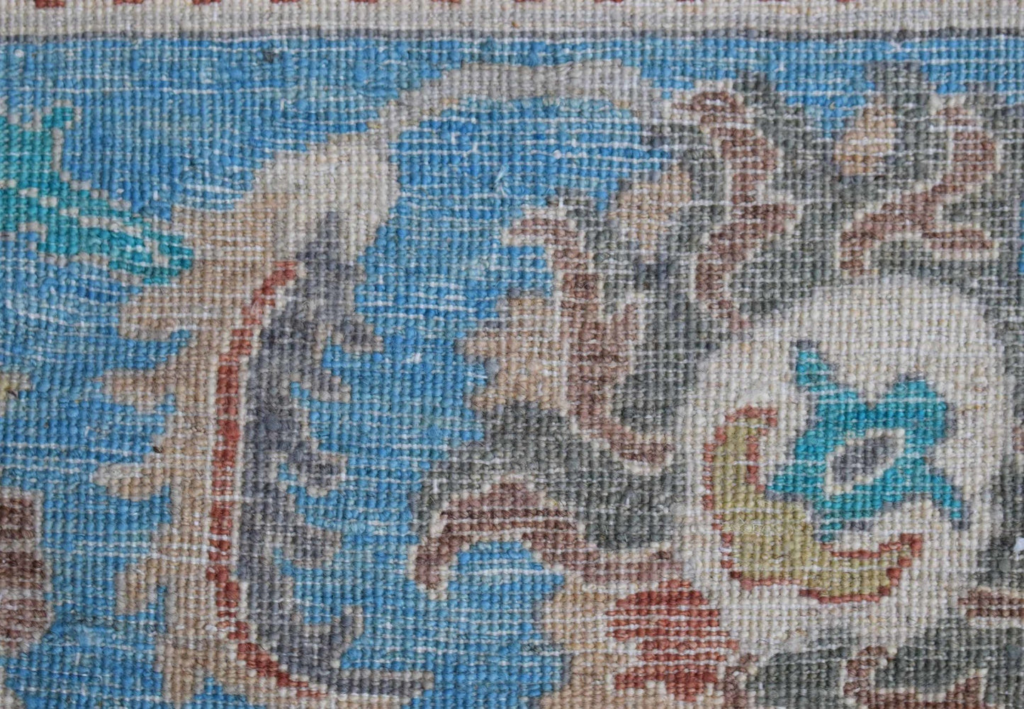 A close-up view of a handwoven Afghan Chobi rug featuring intricate floral patterns in blue and tan.