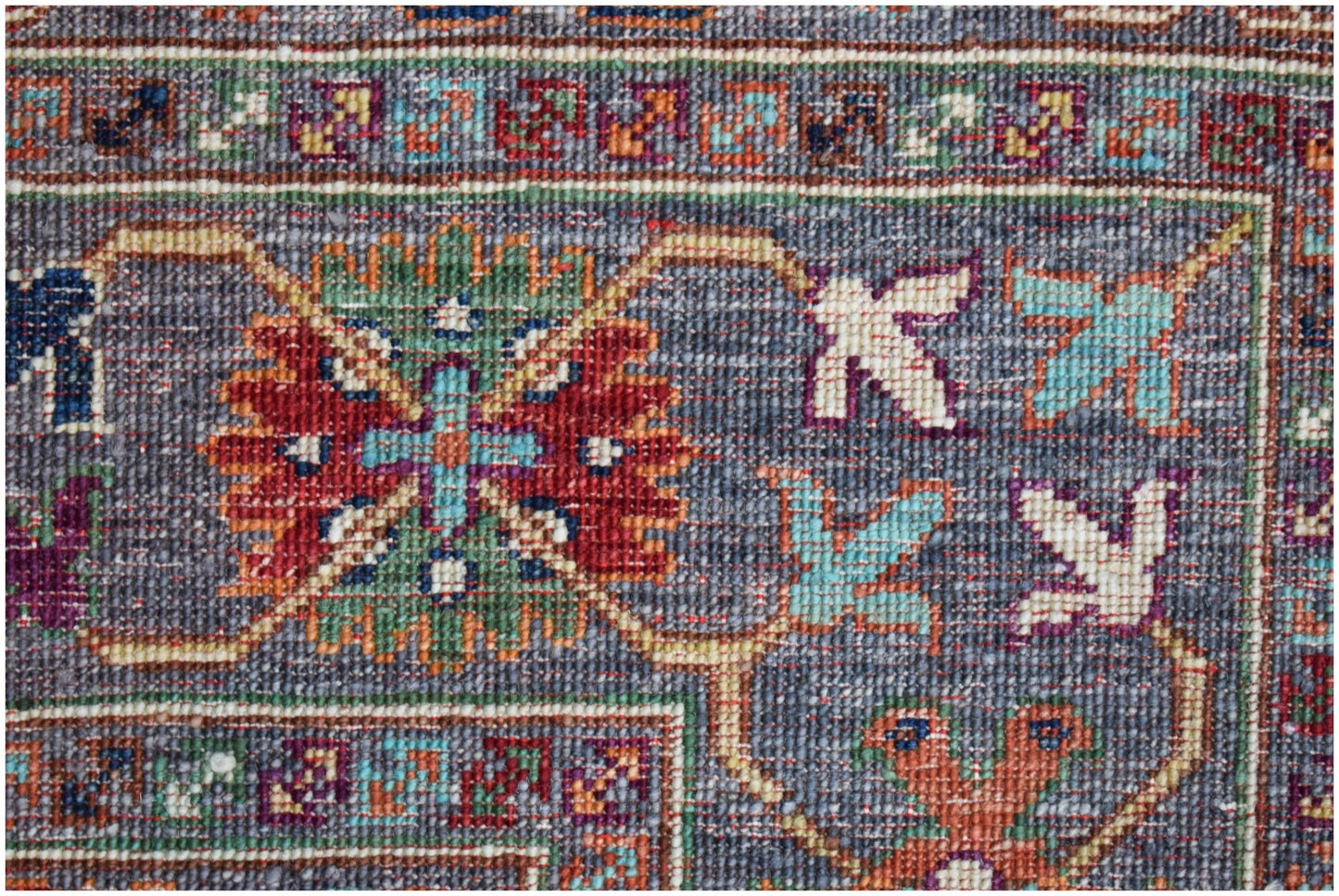A close-up of a handwoven Afghan Chobi rug featuring intricate floral patterns in earthy tones.