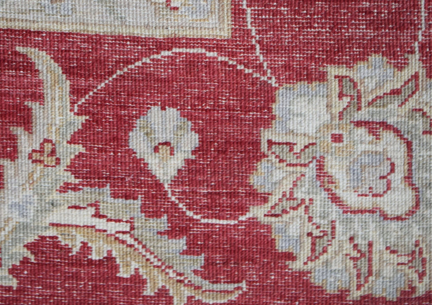 A close-up of a handwoven Afghan Chobi rug featuring intricate floral patterns in red and beige.