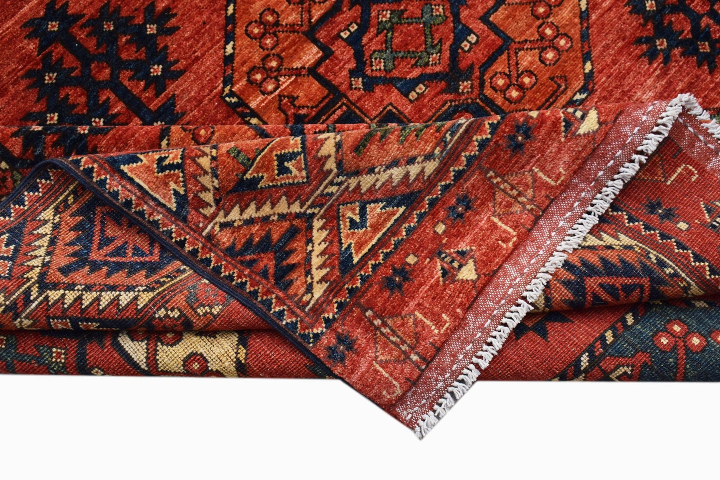 A handmade Afghan Chobi rug featuring traditional geometric patterns in shades of red and blue.