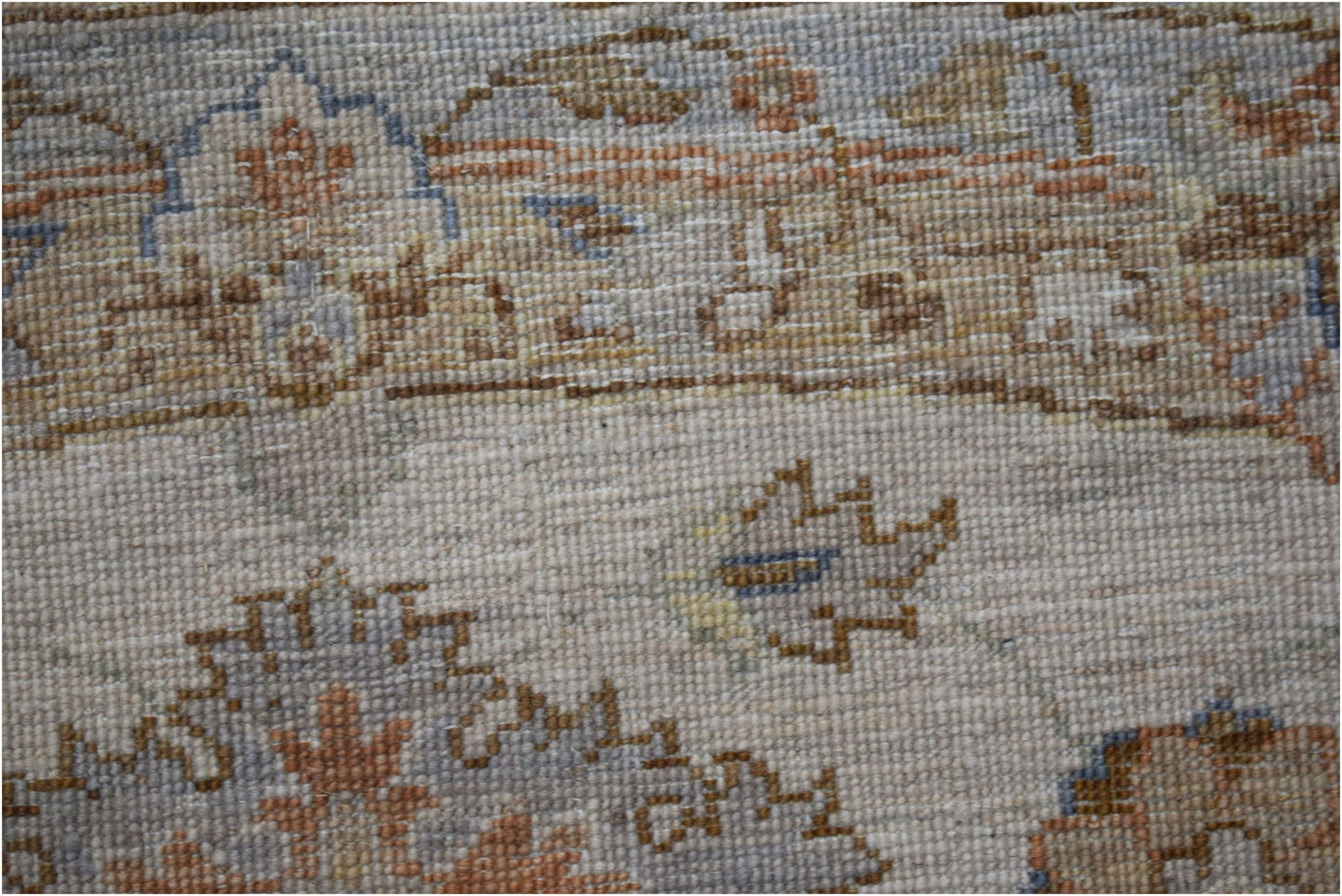 A close-up of a handwoven Afghan Chobi rug featuring traditional floral patterns in earthy tones.