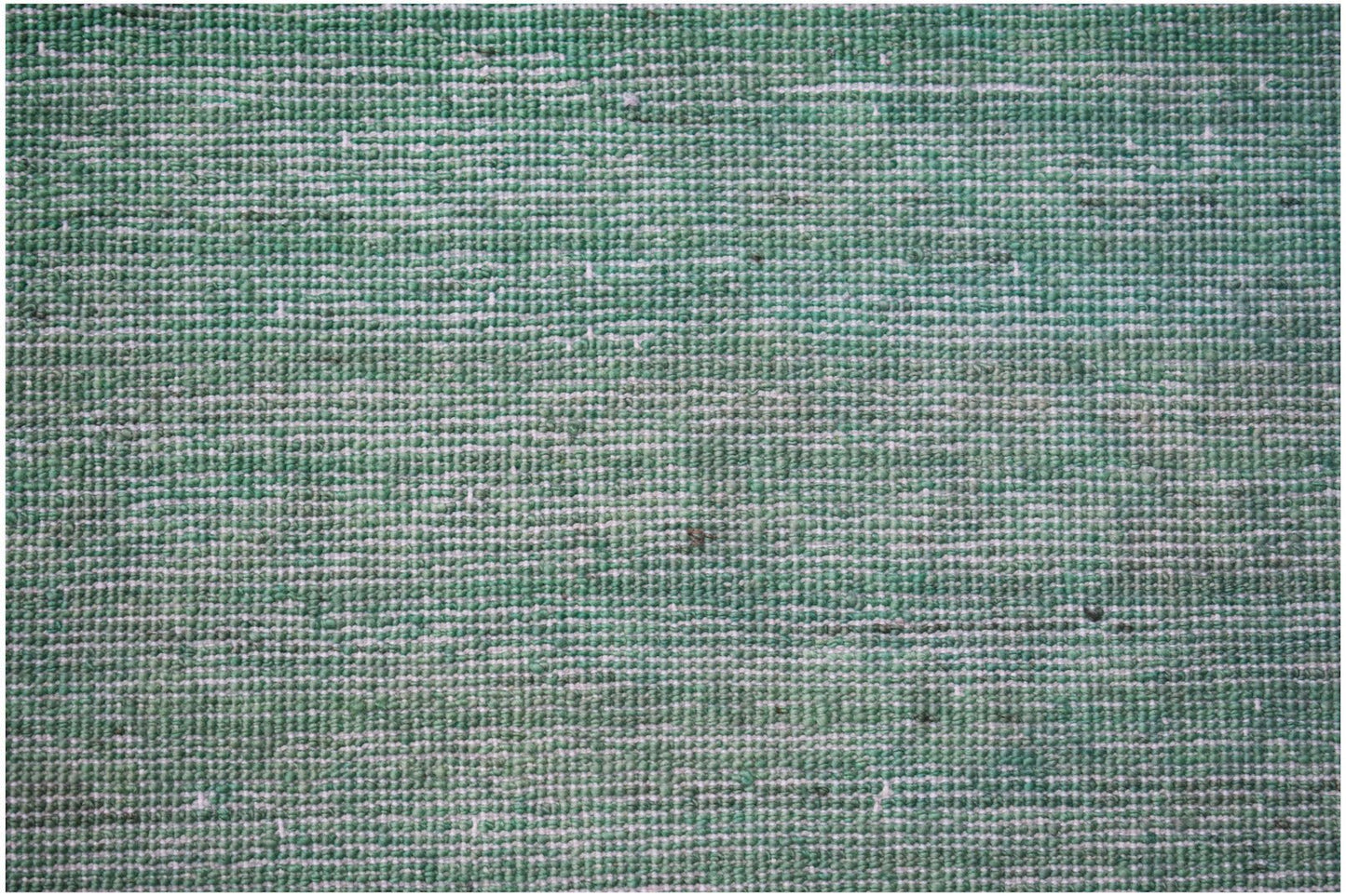 A close-up of a handwoven Afghan Chobi rug featuring a textured, overdyed green wool surface.
