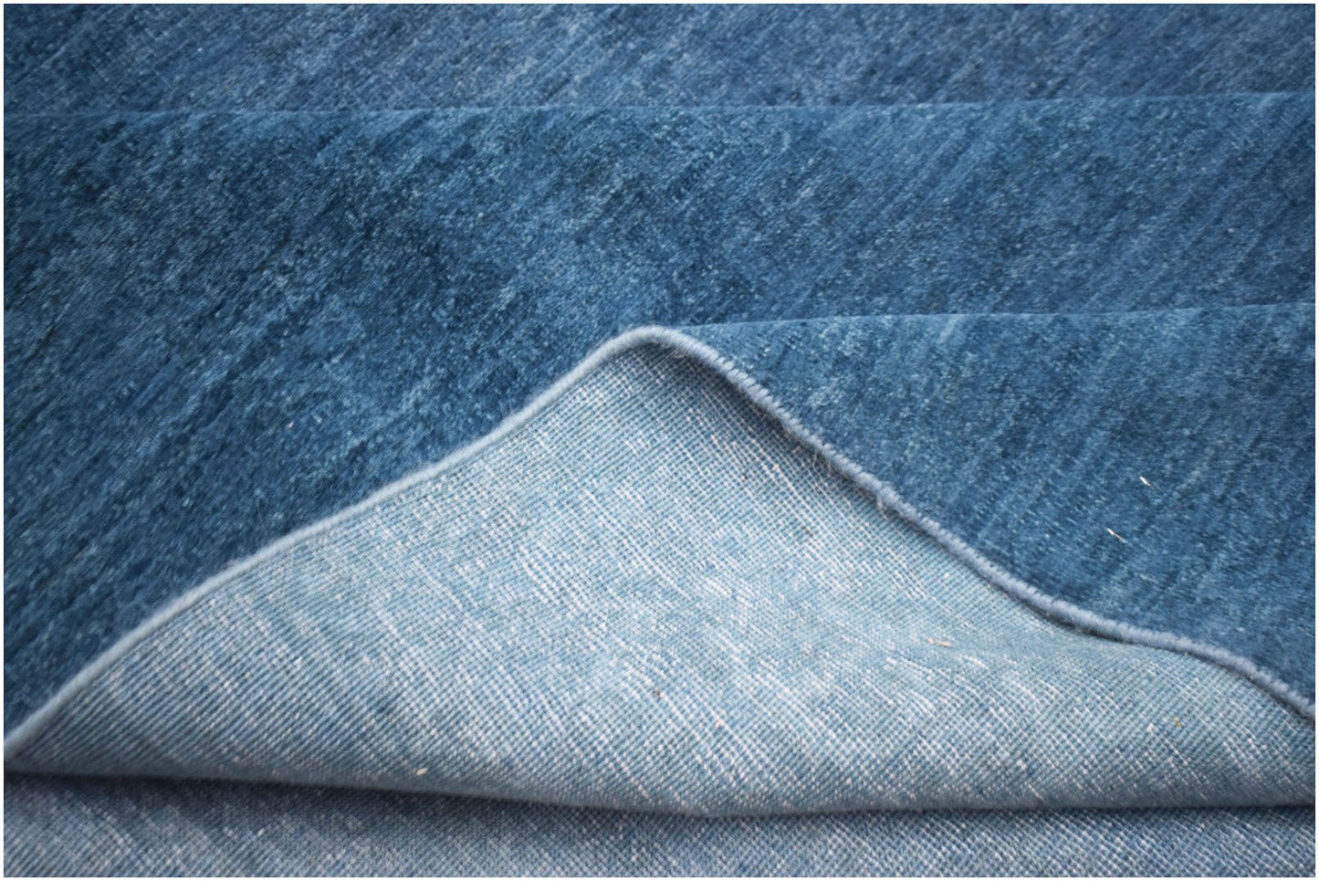 A close-up of a handwoven blue Afghan Chobi rug showing its textured wool pile and cotton backing.