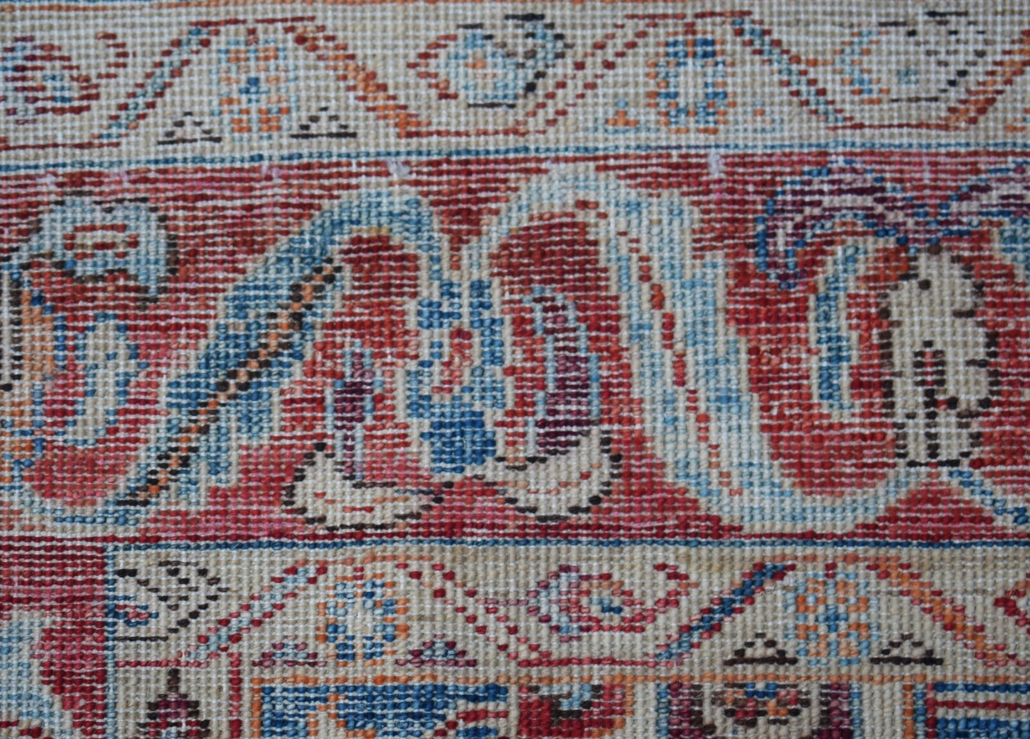 A close-up of an Afghan Chobi rug featuring intricate traditional patterns in red, blue, and cream.