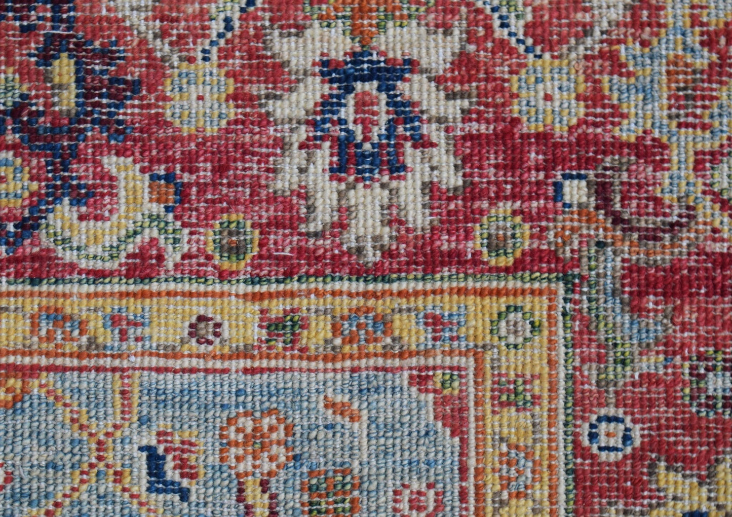 A close-up of a handwoven Afghan Chobi rug featuring intricate floral patterns in red and blue.