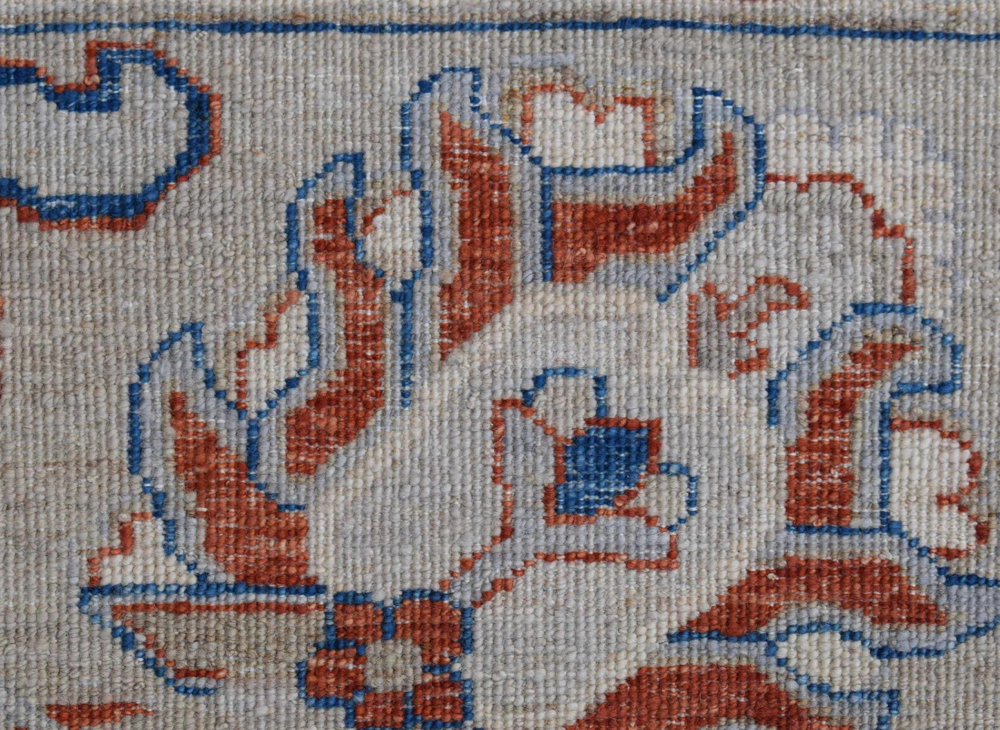 A close-up of an Afghan Chobi rug featuring intricate floral patterns in rust and blue wool.