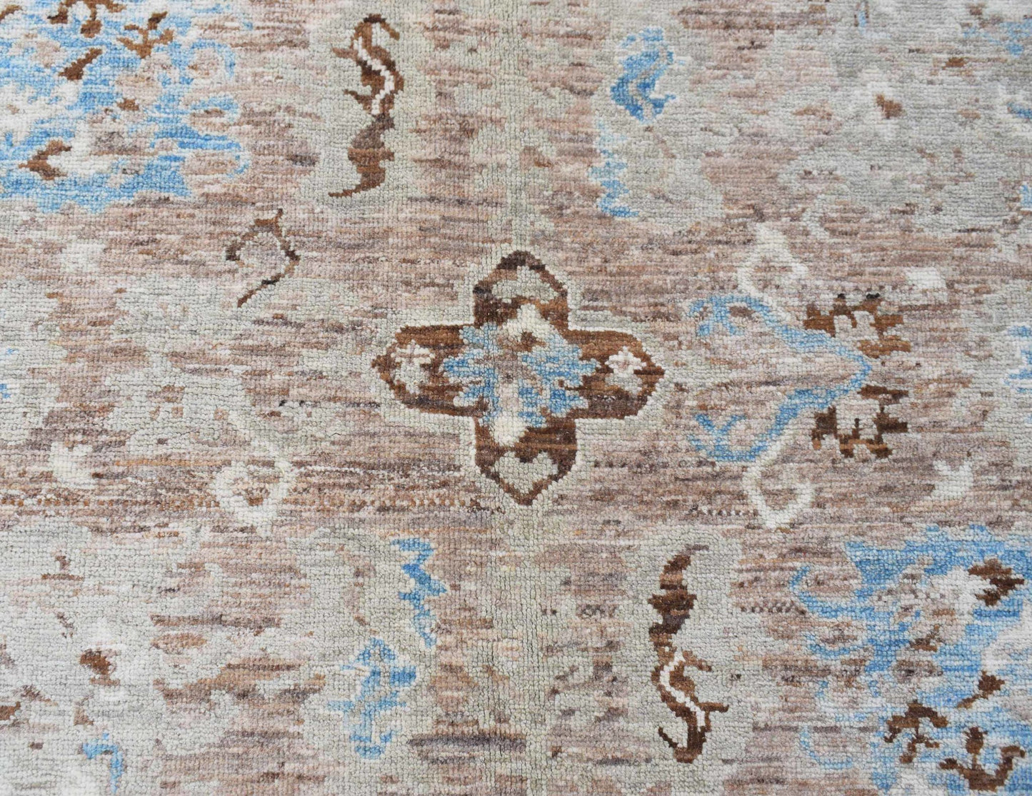 A transitional Oushak rug featuring a brown and blue geometric floral pattern on a wool pile.