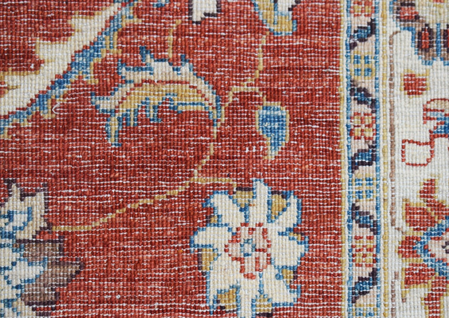A close-up of an Afghan Chobi runner featuring intricate floral patterns in red, blue, and cream.