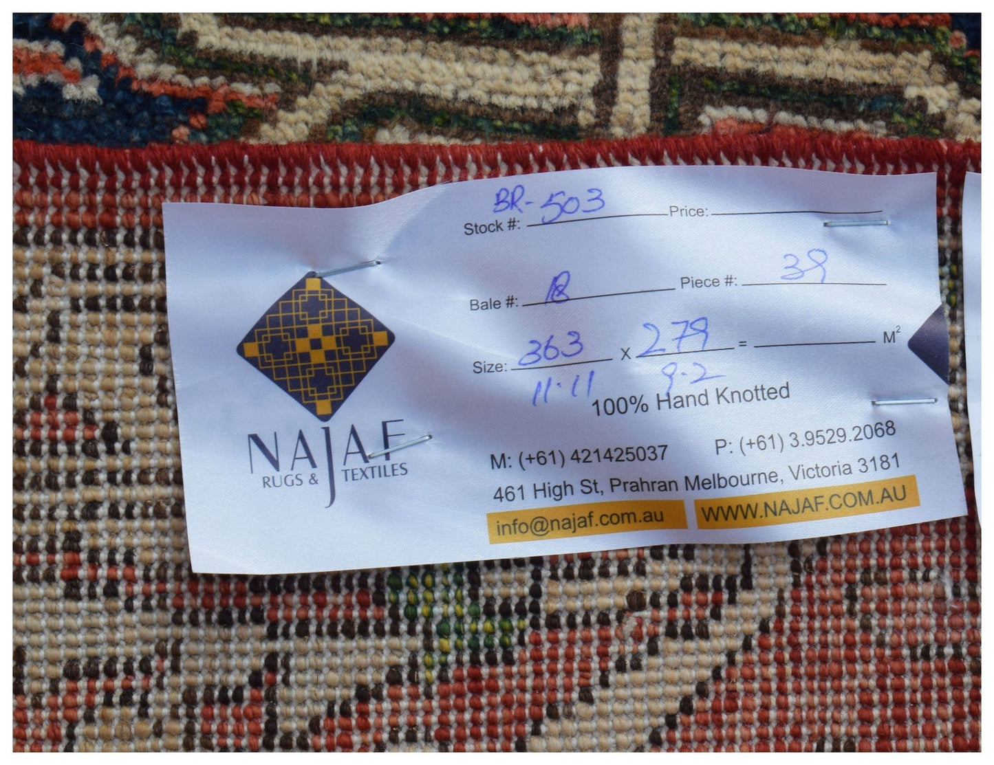 A close-up view of the back of a hand-knotted Afghan Chobi rug with a product information tag.