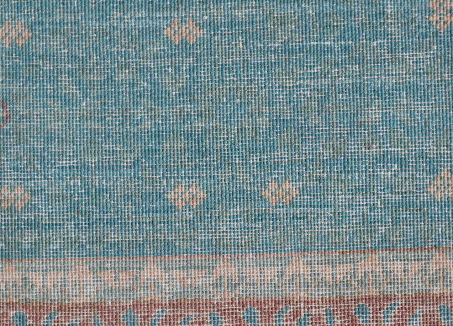 A close-up of a handwoven Afghan Balkh rug featuring a blue field with subtle geometric patterns.