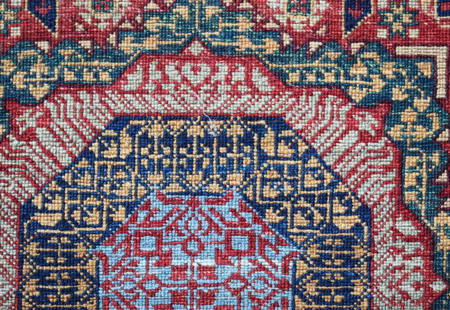 A close-up of an Afghan Chobi rug featuring a detailed Mamluk medallion in red, blue, and gold.