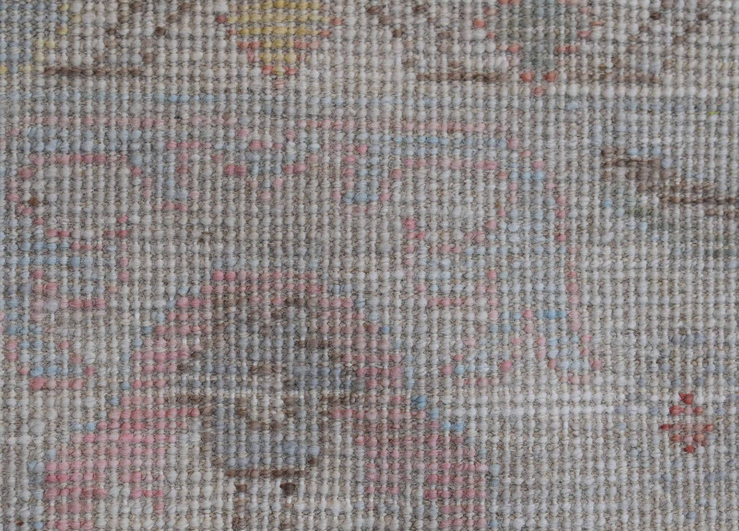 A close-up view of a transitional Oushak rug featuring a soft, floral pattern in muted tones.