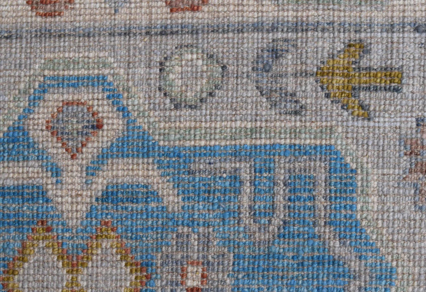 A close-up view of a handwoven Afghan Chobi rug featuring intricate blue and earthy geometric motifs.