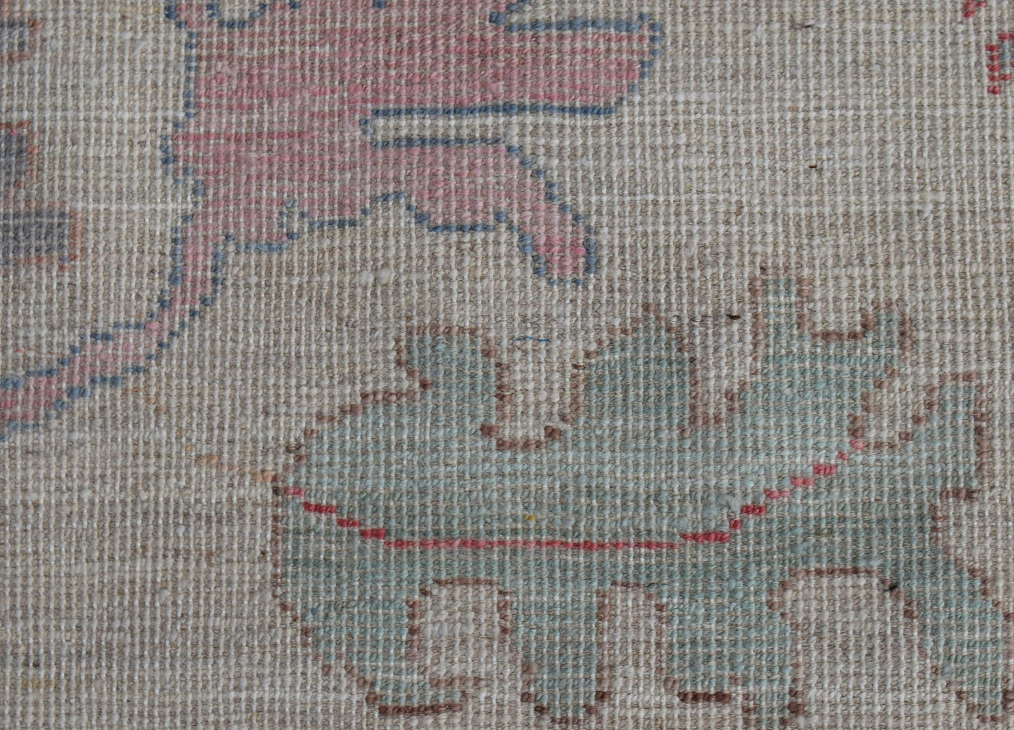 A close-up view of a handwoven wool rug featuring stylized pomegranate motifs in soft tones.