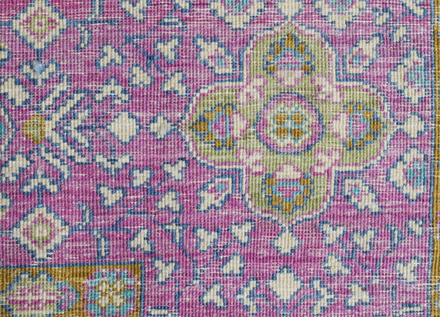 A close-up of an Afghan Balkh rug featuring a traditional floral pattern in shades of pink, green, and blue.