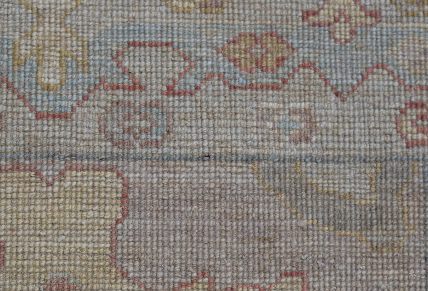 A close-up view of a handwoven wool runner rug featuring a soft floral pattern in muted tones.