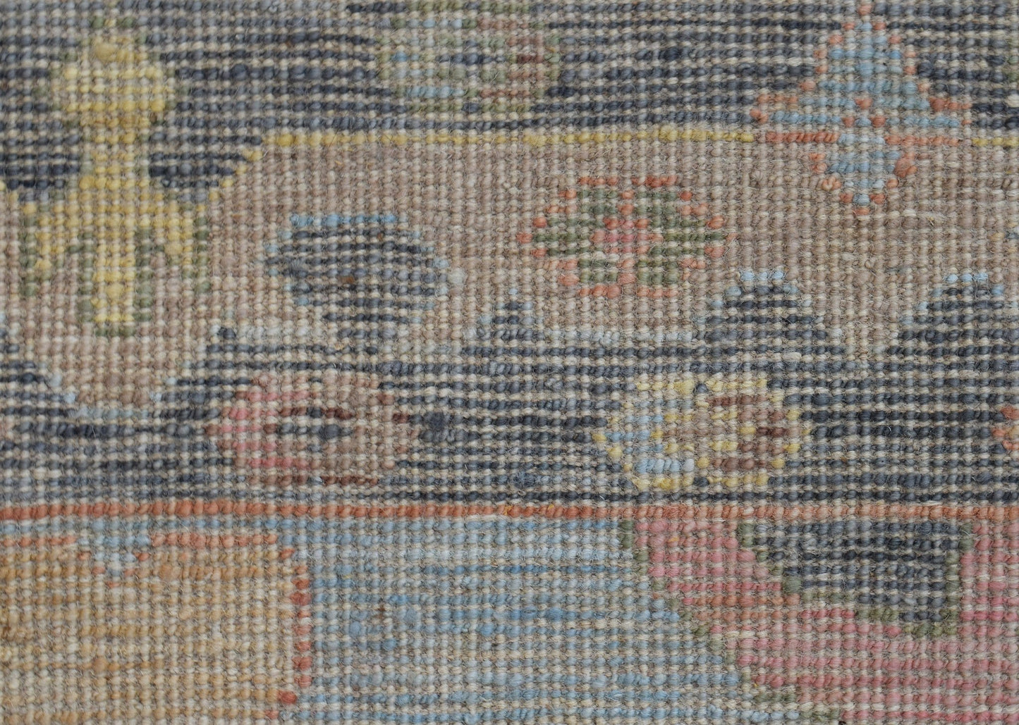 A close-up of a handwoven wool runner featuring a transitional Oushak pattern in muted tones.