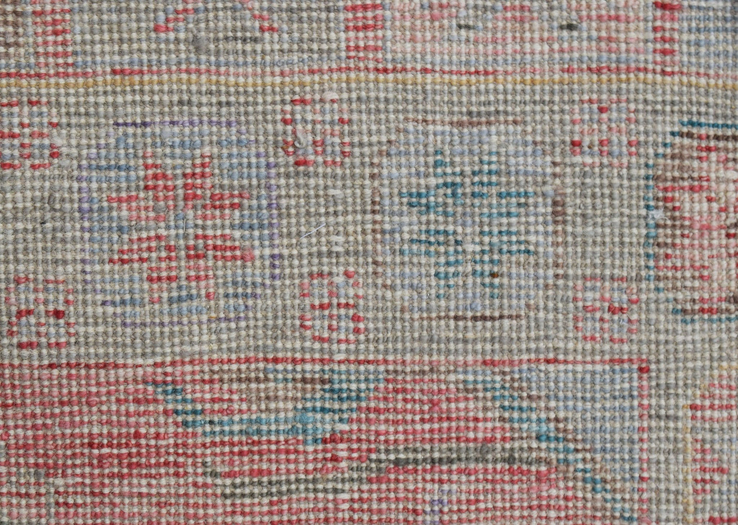 A close-up of a handwoven wool runner featuring a transitional pattern in muted, colorful tones.