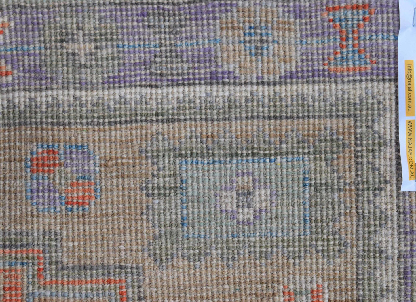 A handwoven transitional Oushak rug featuring a muted, multi-colored geometric pattern.
