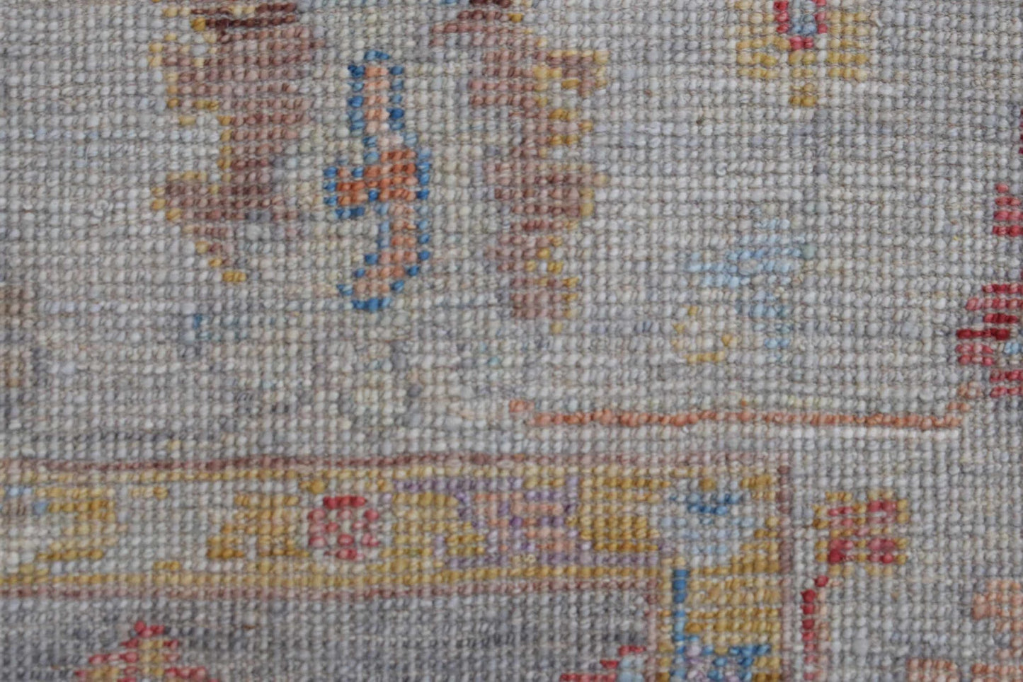 A close-up view of a handwoven transitional Oushak rug featuring a textured wool pile.