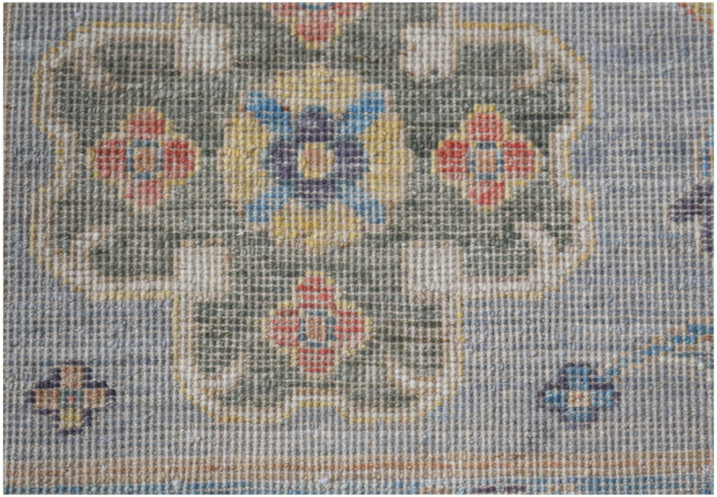 A handwoven transitional Oushak rug featuring a floral pattern in muted tones on a blue background.