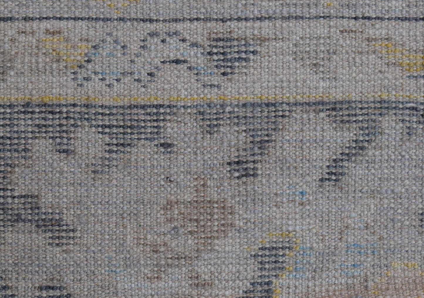 A handwoven wool Oushak rug featuring a transitional pattern in grey, blue, and yellow tones.